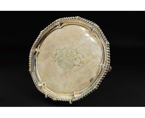 A GEORGE III PAUL STORR SILVER SALVER, gadrooned and pie crust rim, the centre engraved with coat of arms and crest, on four 