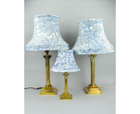 A NEAR PAIR OF EARLY 20TH CENTURY BRASS CORINTHIAN COLUMN TABLE LAMPS, on stepped square bases, heights to top of column 37cm