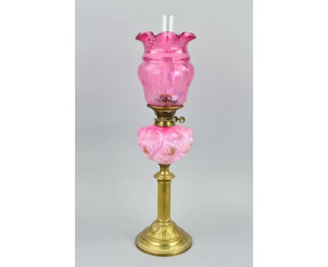 A LATE VICTORIAN BRASS BASED OIL LAMP, with chimney, the cranberry glass shade with acid etched floral decoration, opaque pin