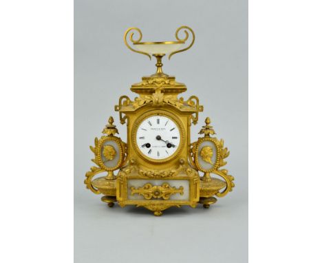 A LATE 19TH CENTURY GILT METAL AND ONYX MANTEL CLOCK, twin handled urn surmount, white enamel dial with Roman numerals named 