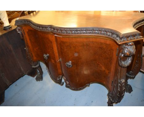 Continental walnut serpentine fronted two door commode having heavily carved decoration on cabriole paw supports, 56.5ins wid