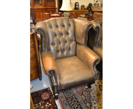 Pair of brown leather button upholstered wing armchairs with loose cushions on cabriole front supports