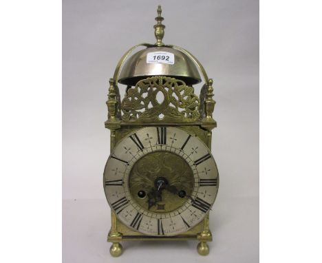 Antique brass lantern clock, the turned finial and bell surmount above a pierced frieze and silvered chapter ring with Roman 