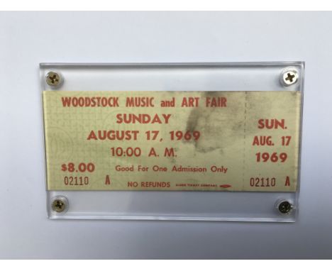 A framed and unused ticket for the Woodstock music festival on Sunday, August 17, 1969 together with a booklet for the film, 