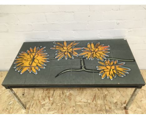 A bold floral decorated tile topped coffee table, small chip to one corner 46x90x40 cm high