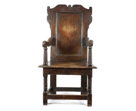 A CHARLES I OAK PANELLED BACK ARMCHAIRYORKSHIRE, C.1640with scroll-carved cresting above a plain back with scroll arms on rin