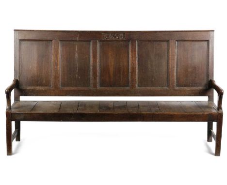 AN OAK SETTLEEARLY 18TH CENTURY AND LATER CARVEDthe quintuple panelled back with the rail later carved with the date and init