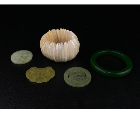 Five items to include a Chinese green jade bangle and three Bi discs along with a mother-of-pearl bracelet. Dia.8cm 