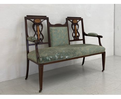 An Edwardian mahogany salon settee or sofa having a stepped top rail with a central upholstered back flanked by a pair of car