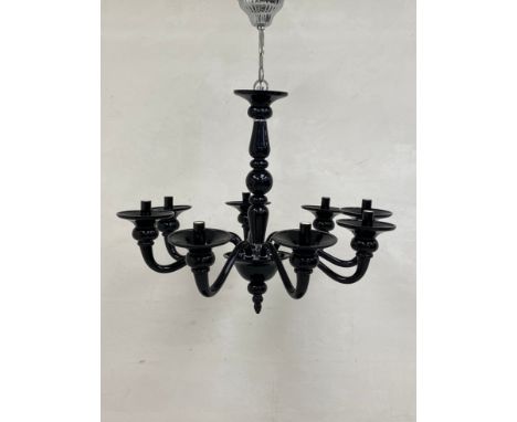 A contemporary black glass chandelier having a baluster form stem with a ball and spire pendant finial and eight simple scrol