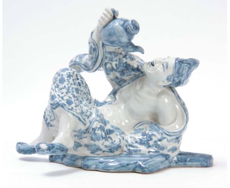 A LATE 19TH CENTURY JAPANESE BLUE AND WHITE PORCELAIN FIGURE depicting a man drinking from a teapot 30cm wide 24cm high. 