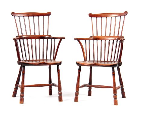 A PAIR OF EARLY 19TH CENTURY YEW- WOOD COMB-BACK WINDSOR CHAIRS with scrolled arms supports, saddle seats and standing on rin