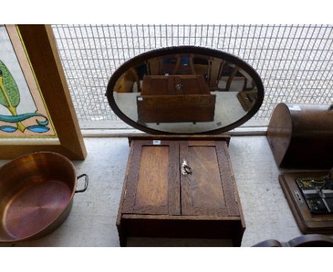 An oval oak framed mirror and wall cabinet