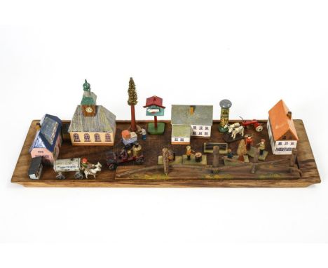 Erzgebirgsdorf mit Figuren und Gespannen, auf Holztablett. Ungemarkt.Holz, farbig bemalt. 48 x 14,5 cm. Maximale Höhe 13,5 cm