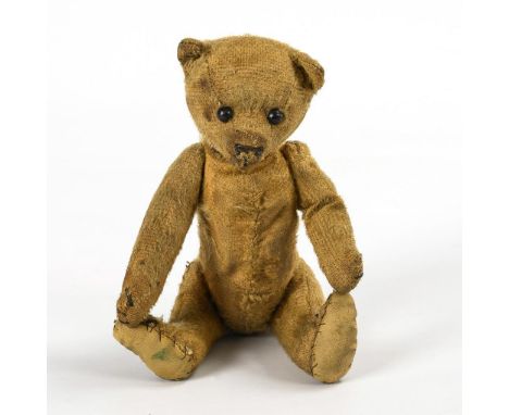 Früher Teddy. Ungemarkt. Um 1910/20.Reste von blondem Mohair. L 21,5 cm. Kleiner, verkahlter Teddybär mit schwarzen Schuhknop