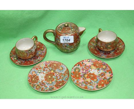 A small Satsuma Teapot, two tea cups and four saucers, decorated with gilt and colourful enamels.