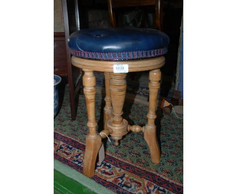 A revolving Piano Stool, on partly turned legs with turned rails and central column embellished with drop mould in a light Oa