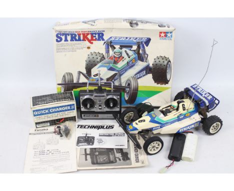 Tamiya - A boxed vintage 1980s radio control Tamiya Striker off road racer in 1:10 scale. It includes 2 x battery packs, a pl