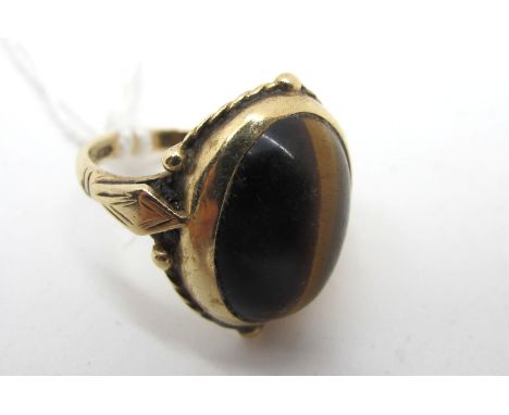 A 9ct Gold Tiger's Eye Single Stone Dress Ring, oval collet rubover set, (finger size M) (4.6grams). 