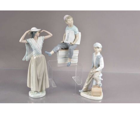 Three Nao by Lladro figurines,  including a paperboy, a shoeshine boy and a lady adjusting her hat. The tallest 31 cm tall. G