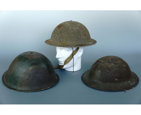 A Second World War British army Mk 2 steel helmet, a post-War camouflaged Mk V helmet, a Fire Watcher's helmet shell and a ga