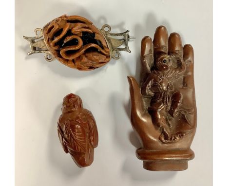 A novelty metal mounted brooch, in the manner of a carved walnut shell, with flying serpent and snake in relief; a carved woo