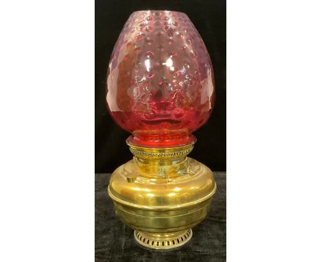 A large brass Veritas oil lamp, cranberry glass shade, 48cm high 