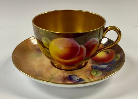 A Royal Worcester cabinet cup and saucer, decorated by B Cox, signed, painted with ripe fruit on a mossy bank, gilded interio