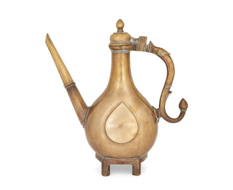 A brass ewer, North India, 18th century, on four raised legs, rising to a pear shaped body with s-scroll handle terminating i