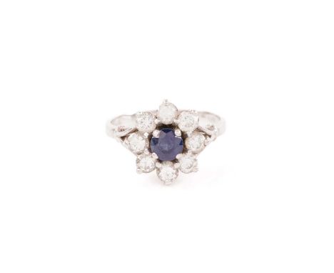 A sapphire and diamond flowerhead ring, comprising a circular-cut sapphire of 4.8 mm, encircled by eight brilliant-cut diamon