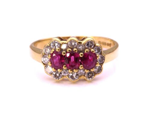 A ruby and diamond cluster ring in 18ct gold, comprising three oval-cut rubies encircled by a frame of diamonds, to a taperin