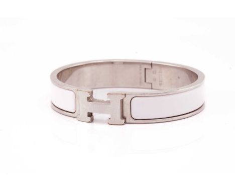Hermès - A narrow 'Clic H' bracelet with pale pink enamel and white metal, signed and marked, overall measuring 6.2 x 5.5 cm,