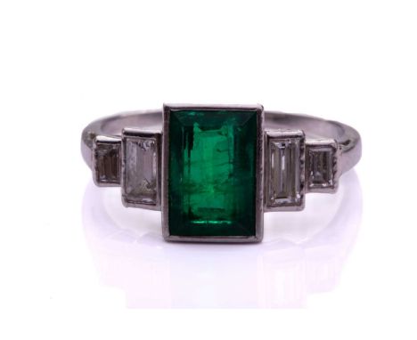 An Art Deco-style emerald and diamond ring, featuring a rectangular step-cut emerald with intense green colour, approximately