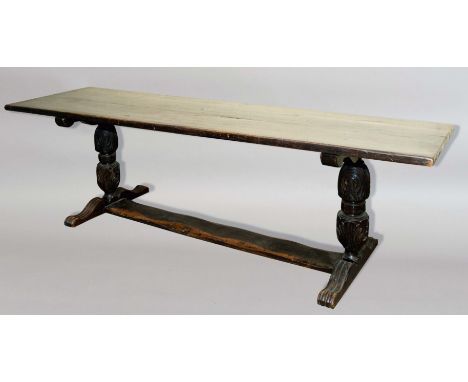 OAK REFECTORY TABLE, the planked top on a foliate carved cup and cover base with scrolling feet and broad floor stretcher, he