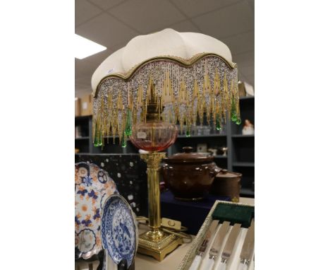 A modern table lamp in an oil light design having brass column support with an Art Deco design beaded shade