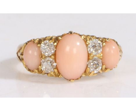 An 18 carat gold "angel skin" coral and diamond set ring, with three cabochon cut corals and four diamonds, ring size K, 3.9g