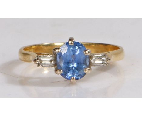 An 18 carat gold and tanzanite set ring, the central round cut tanzanite with a diamond to either shoulder, ring size K, 2.5g