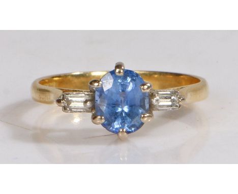 An 18 carat gold and tanzanite set ring, the central round cut tanzanite with a diamond to either shoulder, ring size K, 2.5g