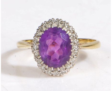 18 carat gold diamond and amethyst ring, the head set with a oval faceted stone surrounded by diamonds, stamped 18ct, ring si