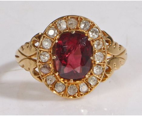 An 18 carat gold ruby and diamond ring, the central oval ruby with a diamond surround, ring size T, 4.9g