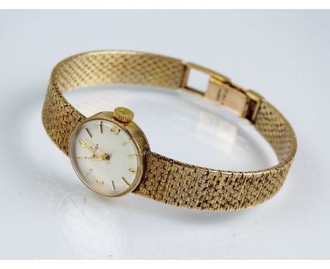 A Lady's 9ct gold Omega bracelet wristwatch, the circular silvered dial with batons, manual wind, integral 9ct gold textured 