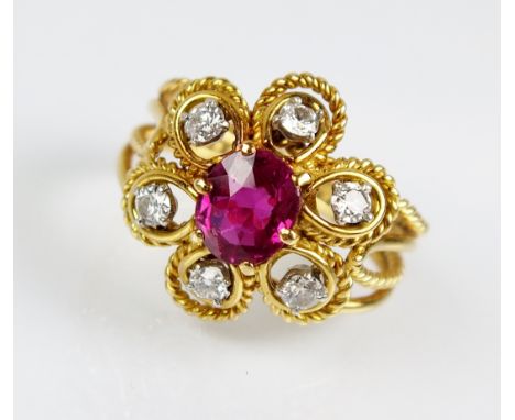 A ruby and diamond floral cluster ring, designed as a central oval mixed cut ruby within a lobed surrround of six brilliant c