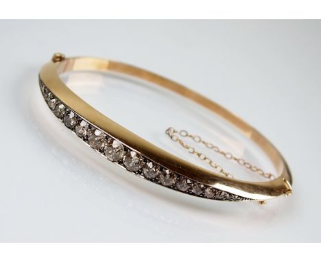 A late 19th century graduated diamond set hinged bangle, designed as a row of nineteen graduated old and eight cut diamonds c