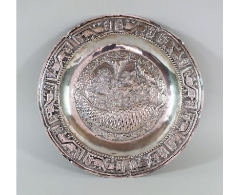 A South American white metal charger, of circular form with embossed stylised Mayan scene to the centre, the reverse stamped 