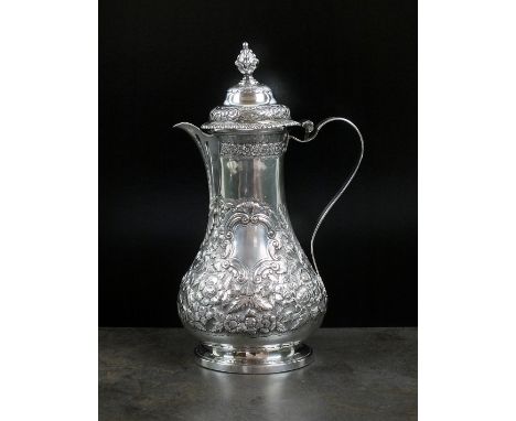 A George III silver hot water jug, IBWB, London 1765, of baluster form with later embossed floral decoration, the domed hinge