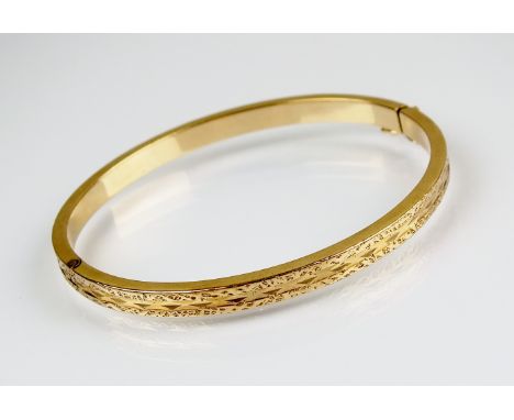 A yellow metal hinged bangle with engraved decoration, with attached safety catch, not stamped, weight 14gms