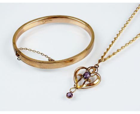 An early 20th century amethyst set pendant, designed as a central oval mixed cut amethyst within a yellow metal openwork moun