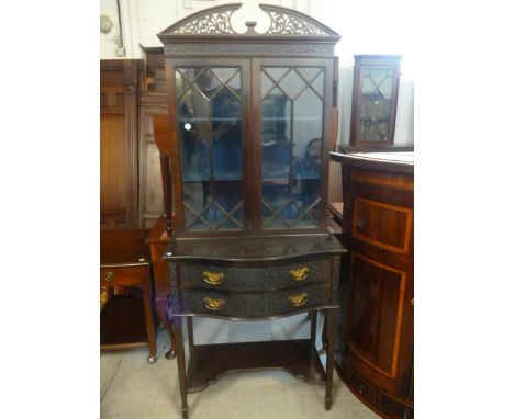 An early 20th century mahogany bookcase cabinet,  with broken secular fretwork cornice, over a serpentine front, blind fretwo