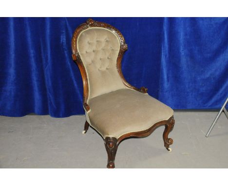 A Victorian walnut nursing chair, having moulded design to frame, with light green upholstery, on short supports with casters