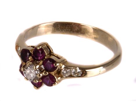 A ruby and diamond flower cluster ring,  the central brilliant within a ruby surround, to brilliant set shoulders, finger siz